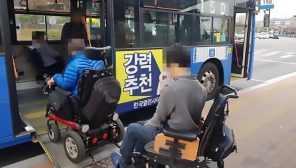 저상버스를 탑승하는 휠체어 장애인들의 모습.